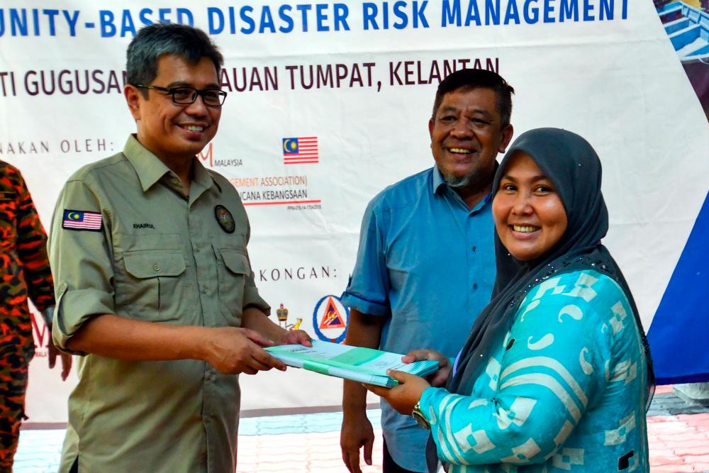 TUMPAT, July 31 -- Deputy Director General of the Post Disaster Management Division, National Disaster Management Agency (Nadma), Datuk Khairul Shahril Idrus (left) presenting a certificate to resident representative Nik Fazilah Mohd Nawi (right) at the Community Based Disaster Risk Management Program Organized by Petronas and the National Disaster Management Association (NADIM) in Teluk Renjuna today. BERNAMAPIX