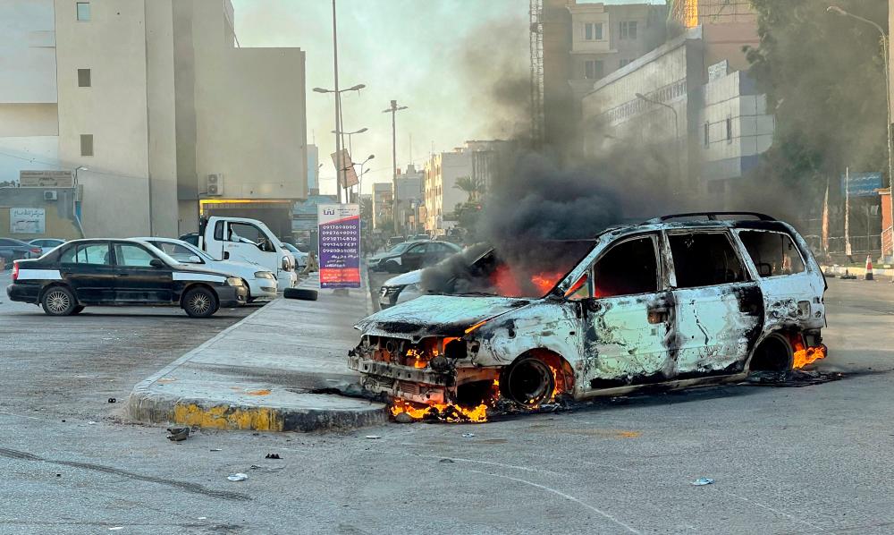 Damaged vehicles are pictured in a street in the Libyan capital Tripoli on August 27, 2022, following clashes between rival Libyan groups. AFPPIX