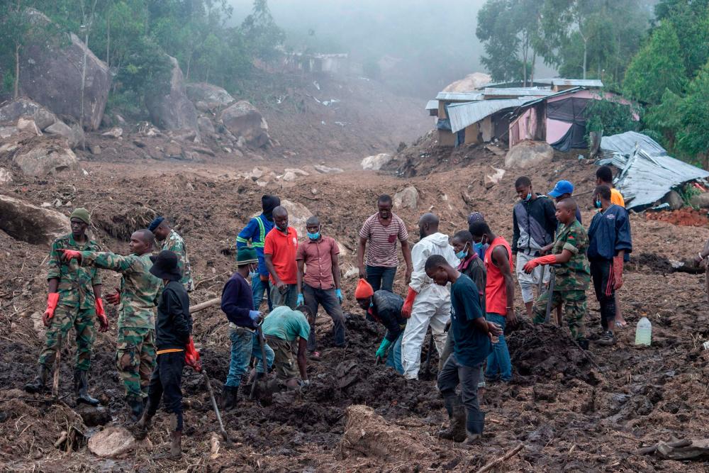 Malawi Defence Force, (MDF) soldiers and civilians work to recover body of a victim of a mudslide which resulted due to heavy rains resulting from cyclone Freddy during an MDF and Malawi Police Service rescue operation at Manje informal settlement up the slopes of Soche Hill in Blantyre, southern Malawi, on March 17, 2023. AFPPIX