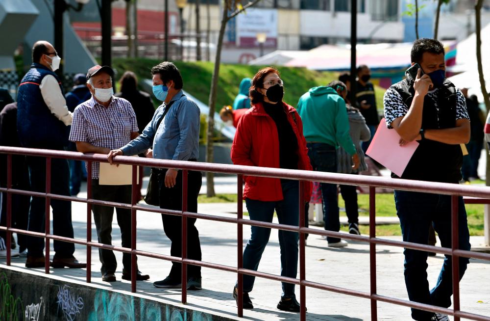 People wearing protective face masks wait in line to carry out errands on the esplanade of the Municipal Palace in Ecatepec, Mexico, on January 24, 2022. AFPPIX