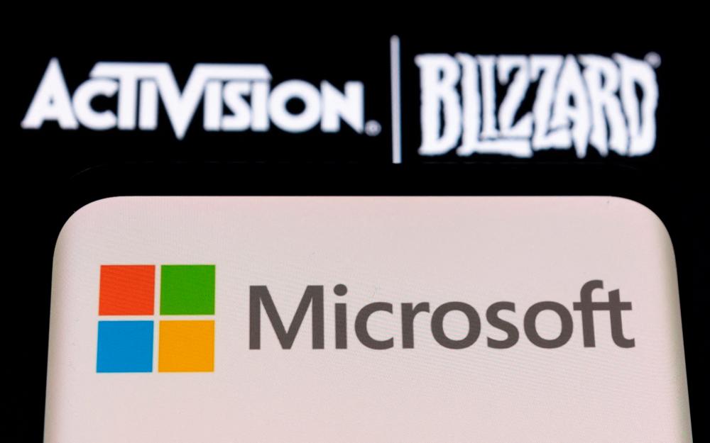 The Microsoft logo is seen on a smartphone placed on displayed Activision Blizzard logo in this illustration. – Reuterspic