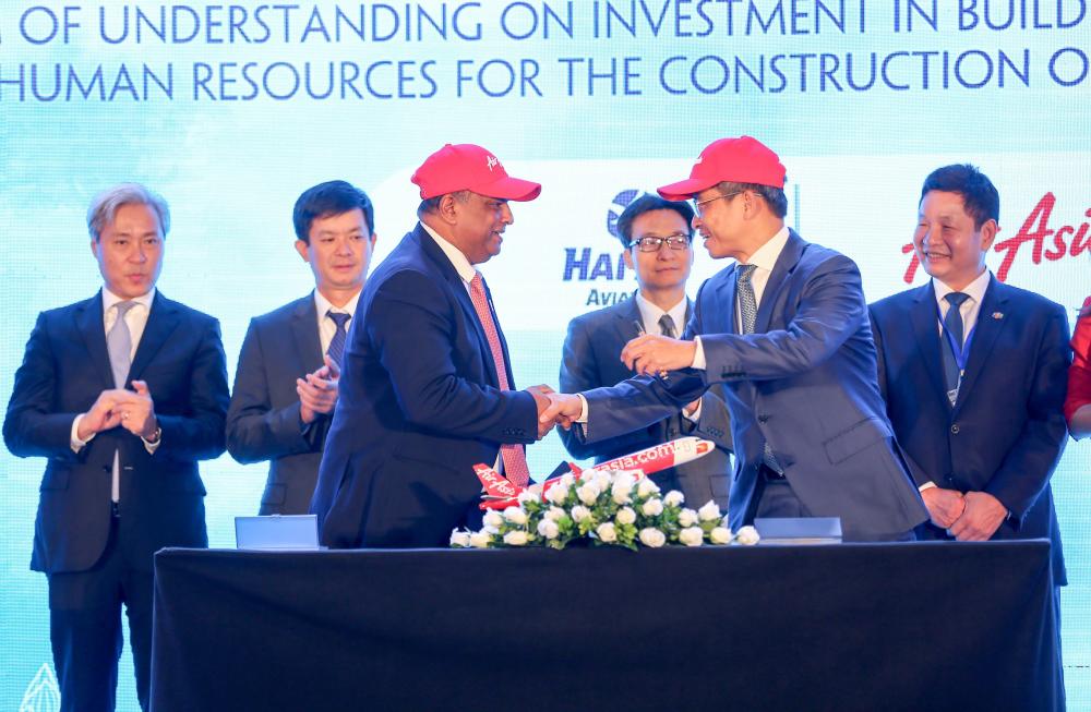 Photo Caption: AirAsia Group CEO Tony Fernandes (front centre left) shakes hands with Tran Trong Kien, CEO of Thien Minh Travel Joint Stock Company CEO and General Director of Hai Au Aviation Joint Stock Company, after the memorandum signing witnessed by Vietnamese Deputy Prime Minister Vu Duc Dam (centre right) and Vietnamese Deputy Minister of Culture, Sports and Tourism Le Quang Tung (centre left), flanked by the Vice Chairmen of the Vietnamese Advisory Council to the Prime Minister on Administrative Procedures Reform, VinaCapital Group CO-Founder and CEO Don Lam (far left) and FPT Corporation Co-Founder, Chairman and CEO Truong Gia Binh (far right), who is also Chairman of Vietnam’s Private Sector Development Committee.