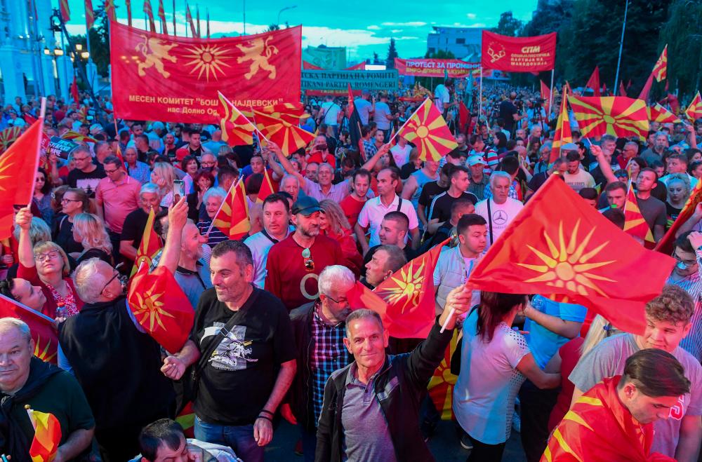 Supporters of North Macedonia's main opposition party VMRO-DPMNE wave party flags and national flags as they march during a rally in front of a government building in Skopje, on June 18, 2022. AFPpix