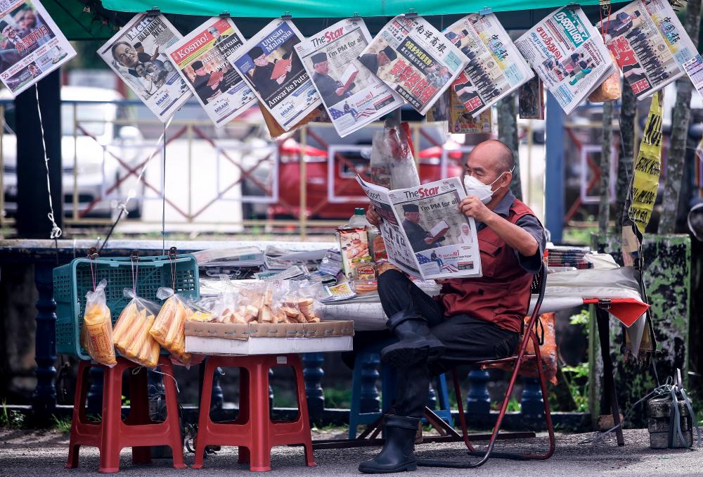 Seorang penjual akhbar membaca berita terkini pada surat khabar yang memaparkan rakaman gambar dan pautan berita pada muka hadapan mengenai pelantikan Pengerusi Pakatan Harapan (PH) Datuk Seri Anwar Ibrahim sebagai Perdana Menteri Malaysia Ke-10 ketika tinjauan, hari ini/fotoBERNAMA