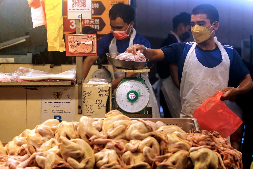 SEREMBAN, May 23 - Workers of fresh chicken stalls weighing chicken pieces ordered by customers at the Seremban Central Market. BERNAMAPIX