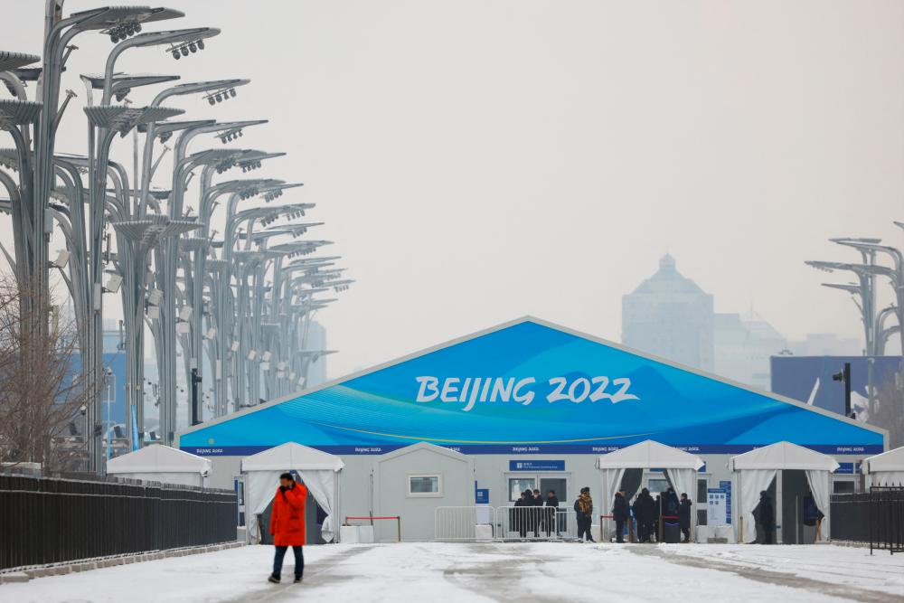 A man walks amid snowfall outside an entrance to the closed loop bubble surrounding venues of the Beijing 2022 Winter Olympics in Beijing, China January 20, 2022. REUTERSpix
