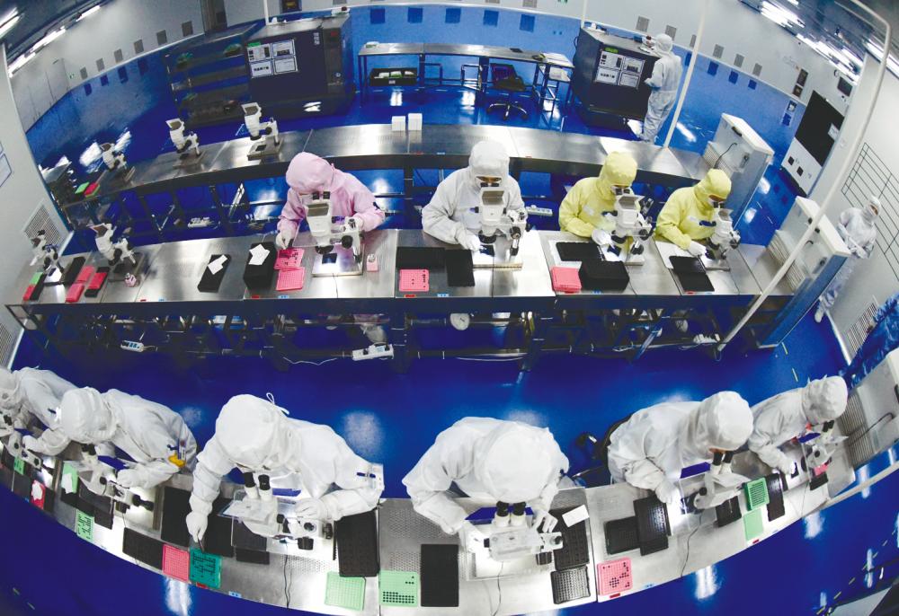 Workers at a production line manufacturing camera lenses for cellphones at a factory in Lianyungang, China. There are risks ahead for China’s manufacturing sector, analysts warned, including shortages of parts and rising commodity prices. – REUTERSPIX