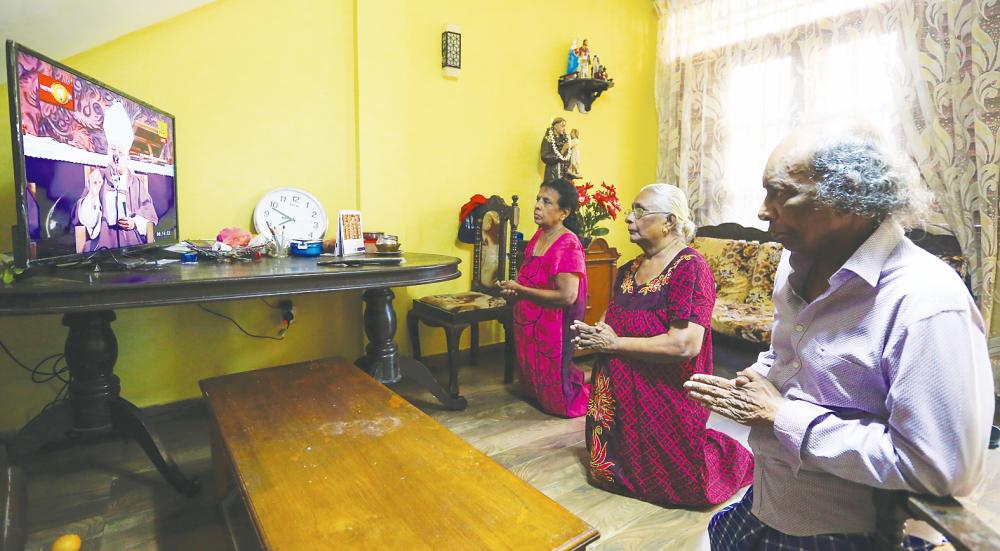 A Sri Lankan Catholic family observes mass at home in Colombo on Sunday. Sri Lanka closed schools, colleges, universities and cinema halls; and it has cancelled all other mass gatherings. – EPApix