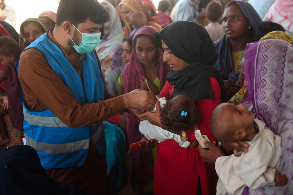 A Pakistani paramedic checks a child at a makeshift medical camp set in Dadu district, Sindh province on September 27, 2022. - AFPPIX