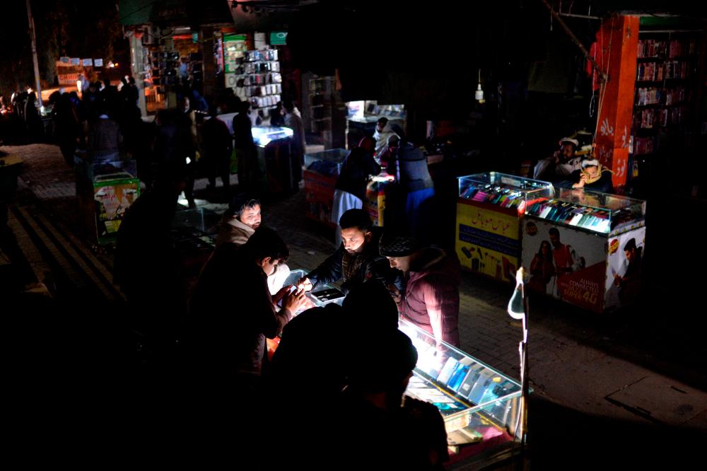 Shopkeepers sit at a market during a nationwide power outage, in Islamabad on January 23, 2023/AFPPix