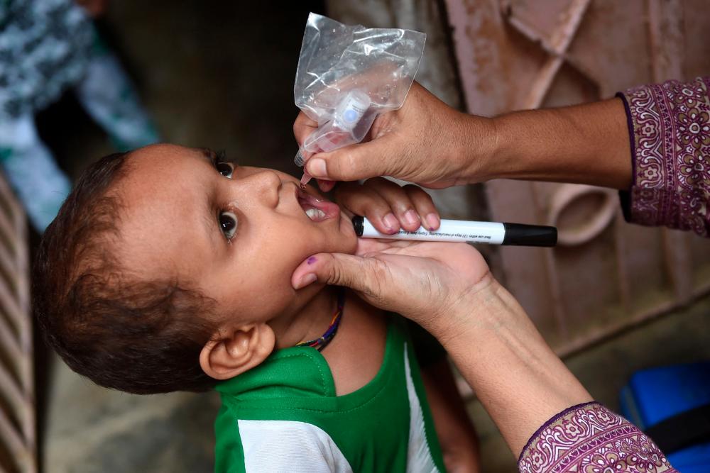 A health worker administers polio drops to a child during a polio vaccination campaign in Karachi on August 15, 2022. - AFPPIX