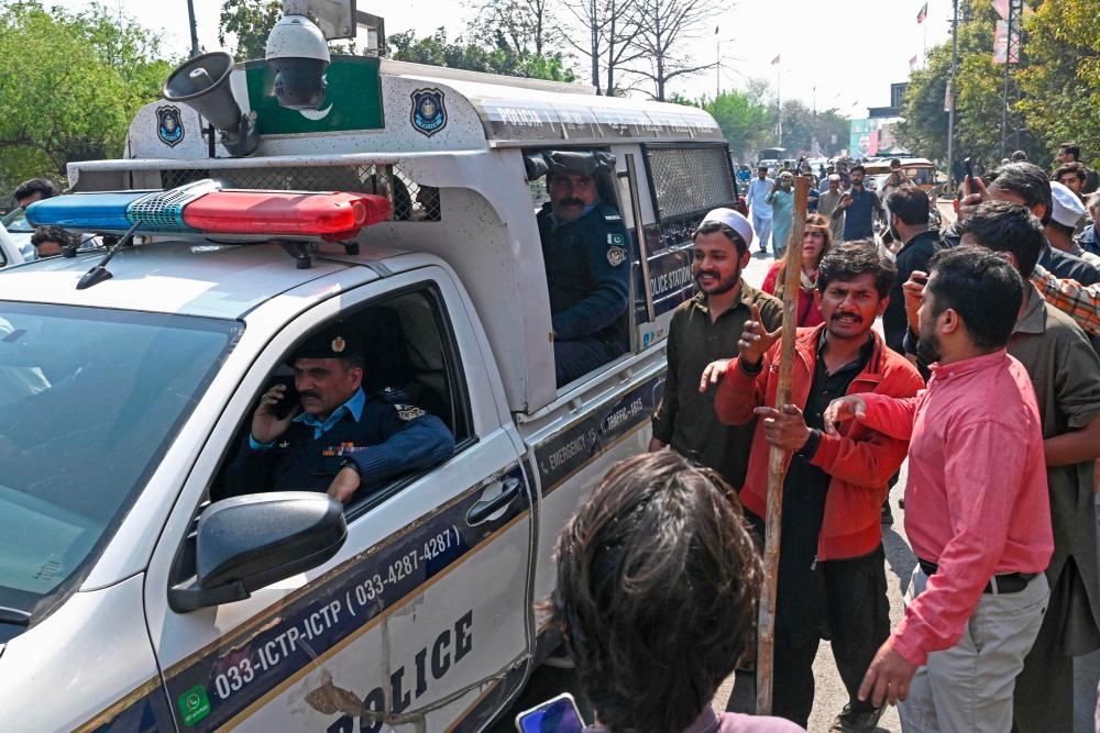 Supporters of former Pakistan’s prime minister Imran Khan gather around police van outside his house in Lahore on March 5, 2023. AFPPIX