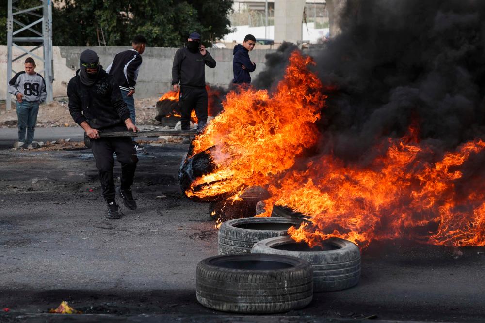 Palestinian protesters burn tyres to block a road leading into Jericho in the occupied West Bank, on February 6, 2023, following a raid in town by Israeli forces. AFPPIX