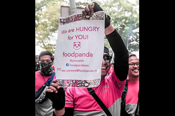 A Foodpanda rider holds up a poster during their ‘stop work’ protest. – Sunpix by Ashraf Shamsul