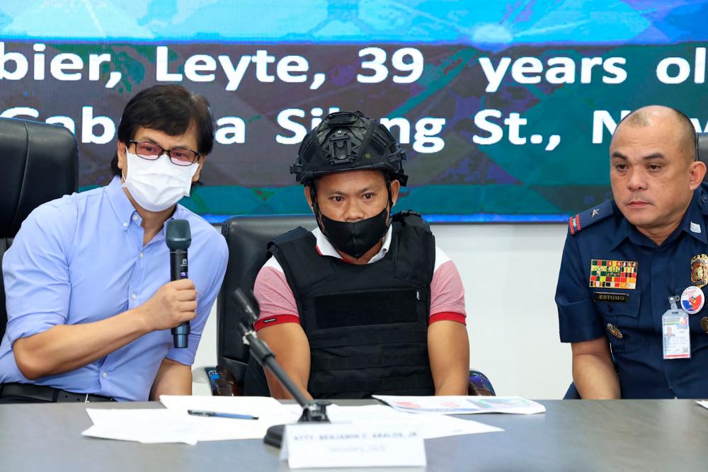 Joel Estorial (C), the alleged gunman in the killing of Philippine journalist Percival Mabasa, is presented to the media as Philippine Interior Secretary Benjamin Abalos (L) speaks during a press conference at the national police headquarters in Manila on October 18, 2022/AFPPix