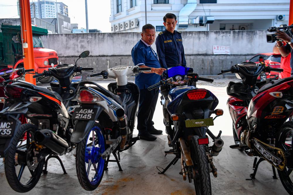 IPOH, 8 August -- Deputy Director of the Perak Road Transport Department (JPJ), Ab Aziz Awang Teh (left) looks at the motorcycles confiscated for various offenses at the OPS Lejang press conference at the Perak State Road Transport Department Office building today. BERNAMAPIX