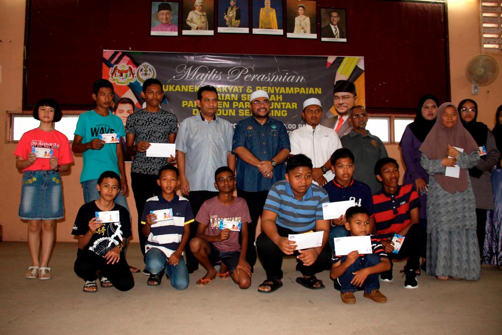 Minister in the Prime Minister’s Department Datuk Seri Dr Mujahid Yusof (standing, 5th from L) pictured with some school uniform voucher recipients from the Parit Buntar parliamentary constituency today. - Bernama