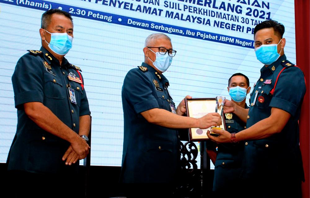 Ketua Pengarah Jabatan Bomba dan Penyelamat Malaysia Datuk Seri Mohamad Hamdan Wahid (dua, kiri) menyampaikan Anugerah Khas Pegawai Cemerlang Berterusan kepada Penolong Penguasa Bomba Mohd Asyraf Mat Isa (kiri) pada Majlis Penyampaian Anugerah Perkhidmatan Cemerlang Tahun 2021 di Ibu Pejabat Jabatan Bomba dan Penyelamat Negeri Perak hari ini/BERNAMAPix