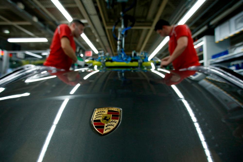 Workers installing the windshield of a Porsche 911 at the carmaker’s factory in Stuttgart-Zuffenhausen, Germany. – Reuterspix
