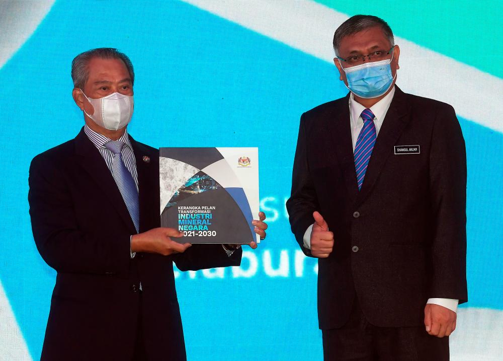 Prime Minister Tan Sri Muhyiddin Yassin shows a book of the National Mineral Industry Transformation Plan 2021-2030 at the launching of the transformation plan today.Also present is Energy and Natural Resources Minister Datuk Seri Dr Shamsul Anuar Nasarah (right).- Bernama