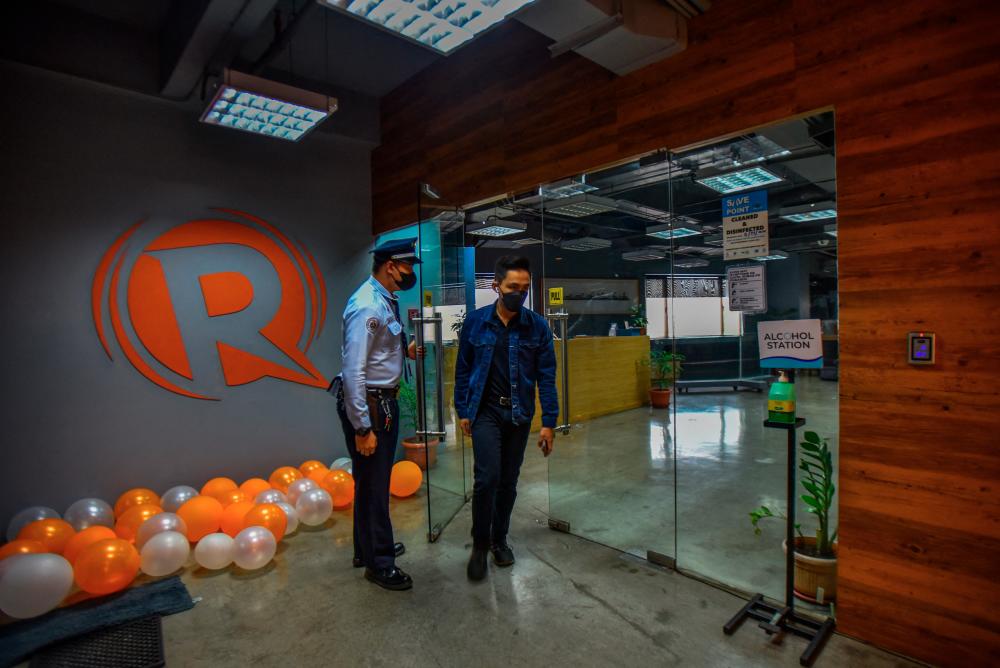 An employee of news online portal Rappler walks past the company logo at their office in Pasig City, suburban Manila. – AFPPIX