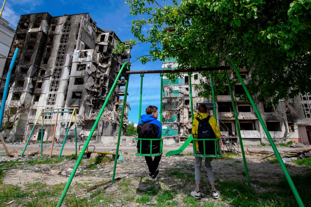 Teenagers Oleskandr and Bohdan sit on swings in front of residential buildings destroyed during Russia’s invasion of Ukraine in the town of Borodianka, in Kyiv region, Ukraine. - REUTERSpix