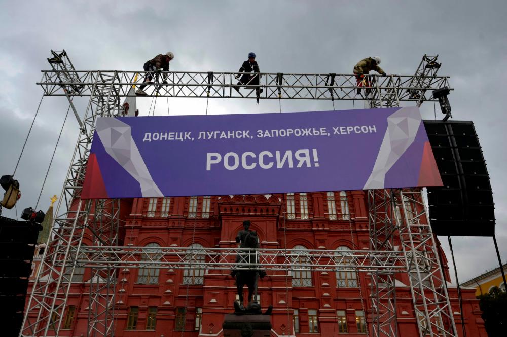 Workers fix a banner reading “Donetsk, Lugansk, Zaporizhzhia, Kherson - Russia!” on top of a construction installed in front of the State Historical Museum outside Red Square in central Moscow on September 29, 2022. Russia will formally annex four regions of Ukraine its troops occupy at a grand ceremony in Moscow on September 30, the Kremlin has announced, after it suggested using nuclear weapons to defend the territories. AFPPIX