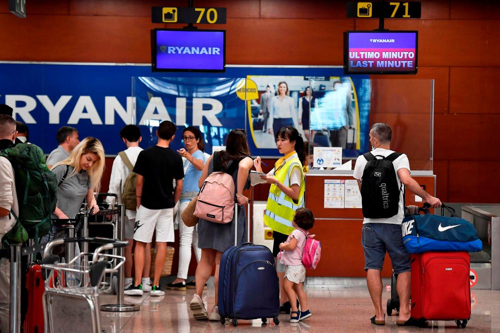 A Ryanair employee talks to a passenger at the check-in counters at the Terminal 2 of El Prat airport in Barcelona on July 1, 2022. AFPpix