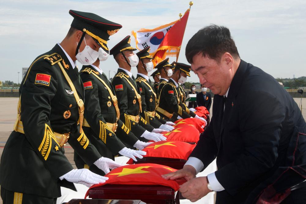Chinese Ambassador to South Korea Xing Haiming (R) covers caskets containing the remains of Chinese soldiers with a Chinese national flag during the handing over ceremony at the Incheon International Airport in Incheon on September 16, 2022. AFPPIX