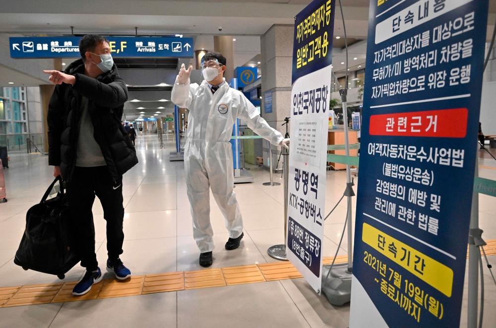 A staff member (C) wearing protective equipment guides a traveller at the arrival hall of Incheon International Airport on November 30, 2021, amid growing concerns about the Omicron Covid-19 variant. AFPpix