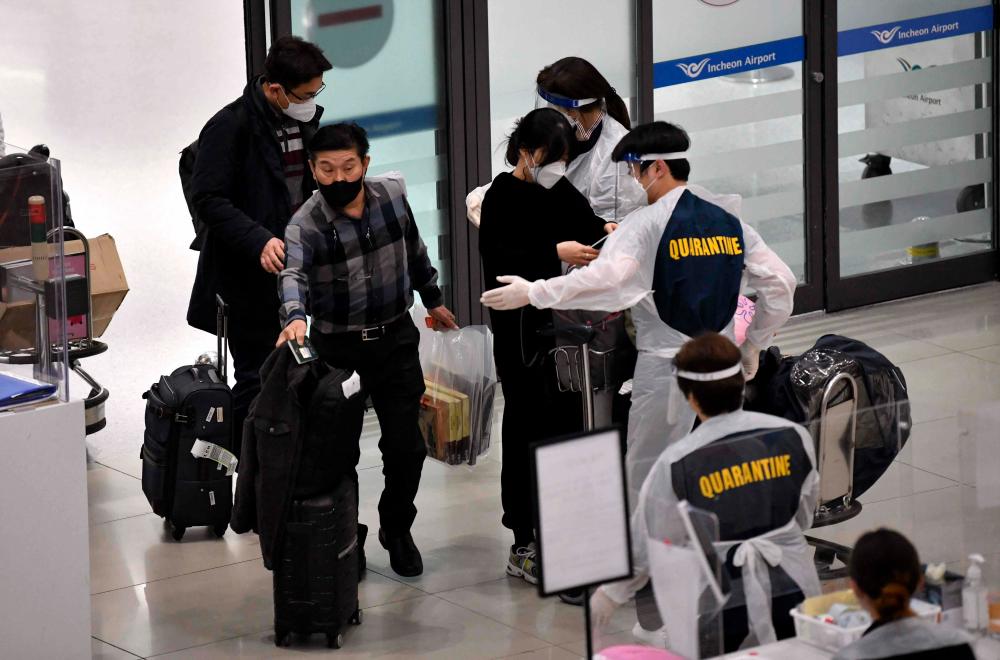 Staff members wearing protective equipment guide travellers at the arrival hall of Incheon International Airport. AFPPIX