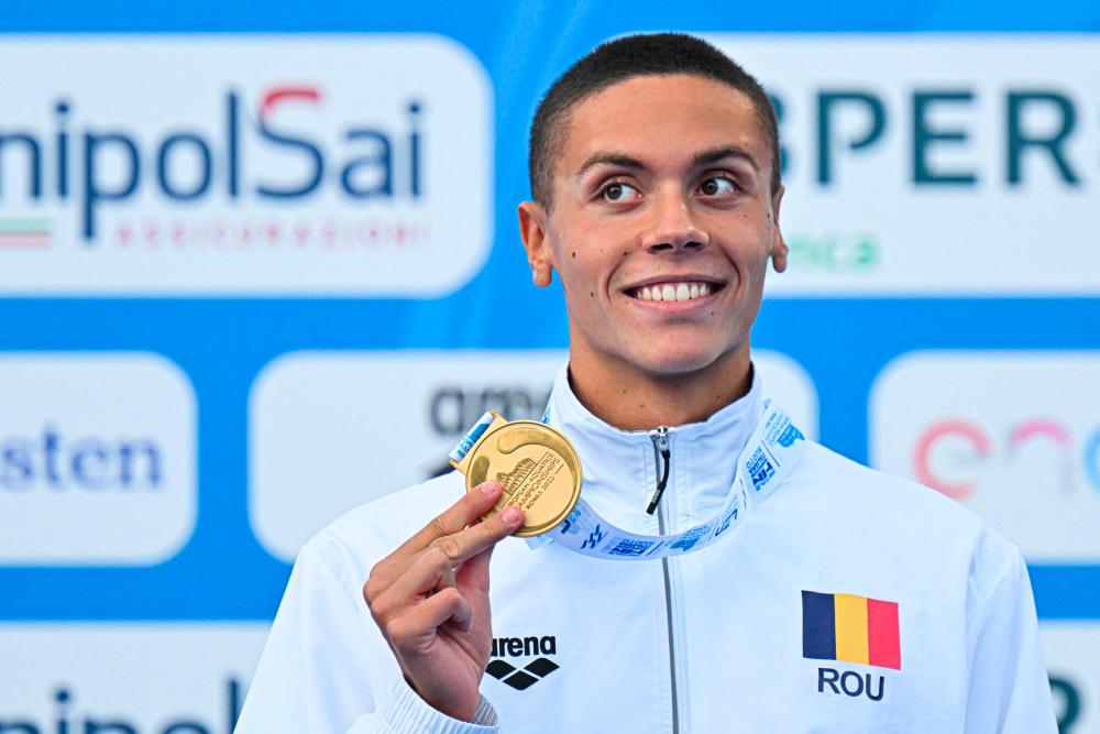 Gold medallist Romania’s David Popovici poses on the podium after winning and setting a new world record of the Men’s 100m freestyle final event on August 13, 2022 at the LEN European Aquatics Championships in Rome. AFPPIX