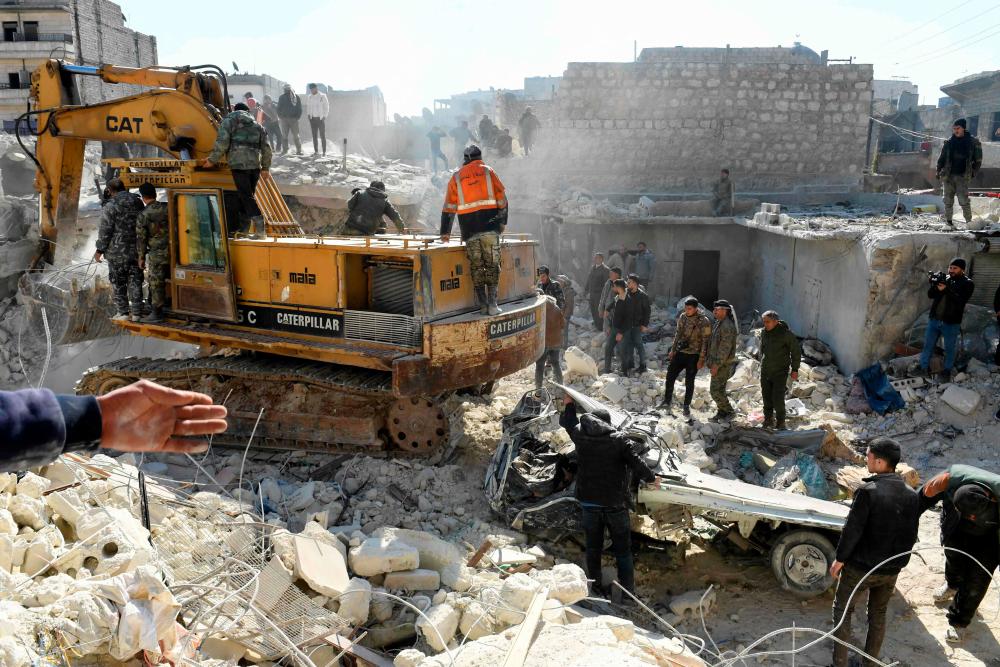 People watch as rescuers sift through the rubble of a building that collapsed in the the northern Syrian city of Aleppo, on January 22, 2023. AFPPIX