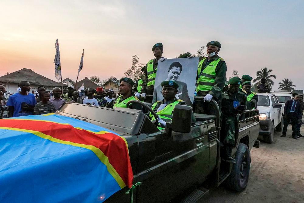 Military personnel hold a portrait of slain Congolese independence leader Patrice Lumumba as they ride in a convoy with his coffin after its arrival at Tshumbe in DRCongo on June 22, 2022. AFPPIX