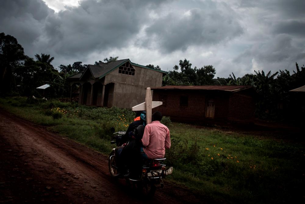 TOPSHOT - Three Congolese ride a motorbike and carry a cross for a grave along the road linking Mangina to Beni on August 23, 2018 in Mangina, in the North Kivu province. AFPpix