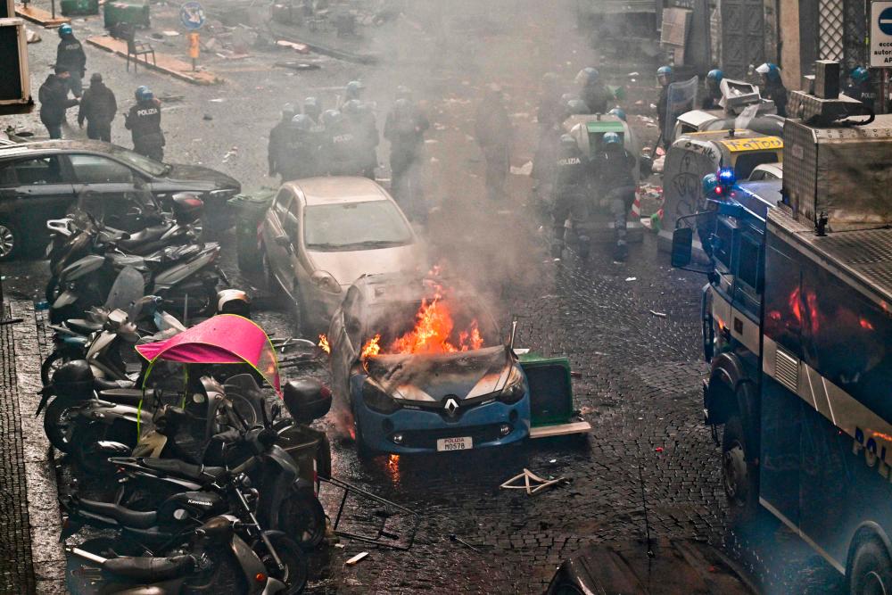 This photo obtained from Italian news agency Ansa shows a police car (Front) burn as Eintracht Frankfurt fans (not in picture) clash with police on March 15, 2023 in downtown Naples prior to the UEFA Champions League round of 16, second leg football match between SSC Napoli and Eintracht Frankfurt to be played at the Diego-Maradona stadium in Naples. AFPPIX