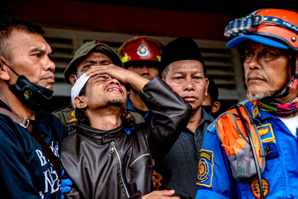Ahmad Ashikin (2L), father of seven-year-old Indonesian girl Ashika Nur Fauziah, reacts after rescue personnels found her dead under the rubble at Cugenang village, in Cianjur, on November 25, 2022. AFPPIX