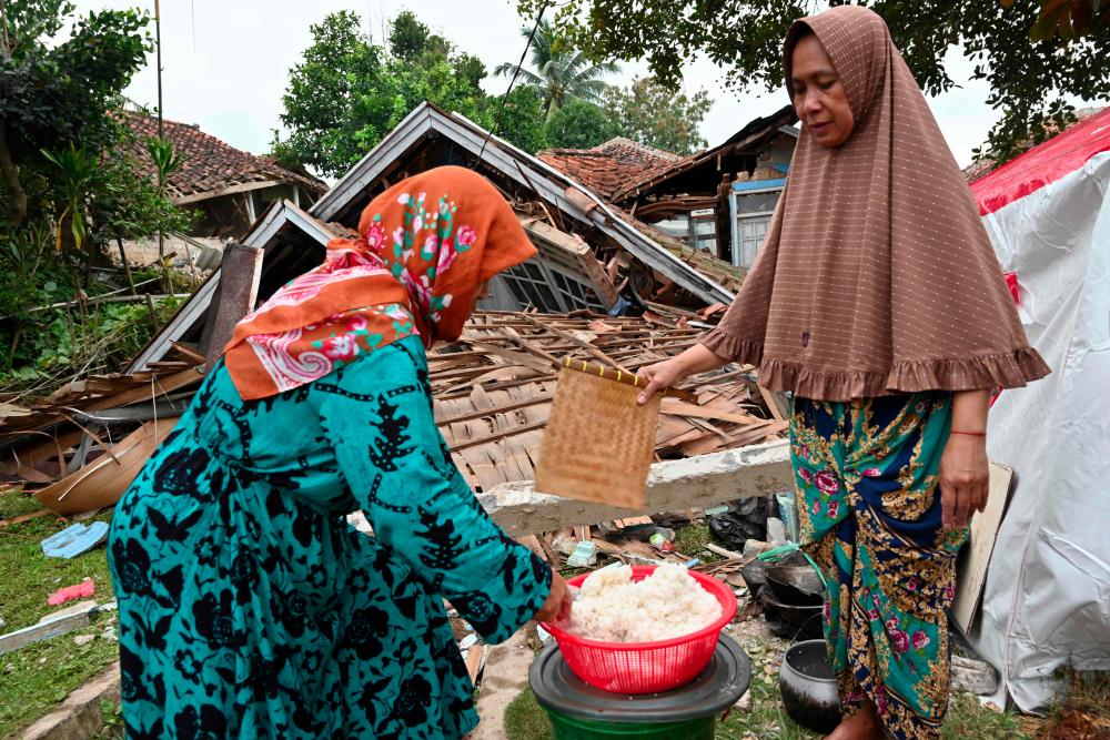 TOPSHOT - Women cook beside the rubble of a collapsed house in Cugenang, Cianjur on November 23, 2022, following a 5.6-magnitude earthquake on November 21. - AFPPIX