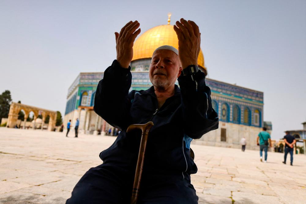 TOPSHOT - A Palestinian man prays in front of the Dome of Rock mosque at the Al-Aqsa mosque compound in Jerusalem's Old City on April 17, 2022. AFPPIX