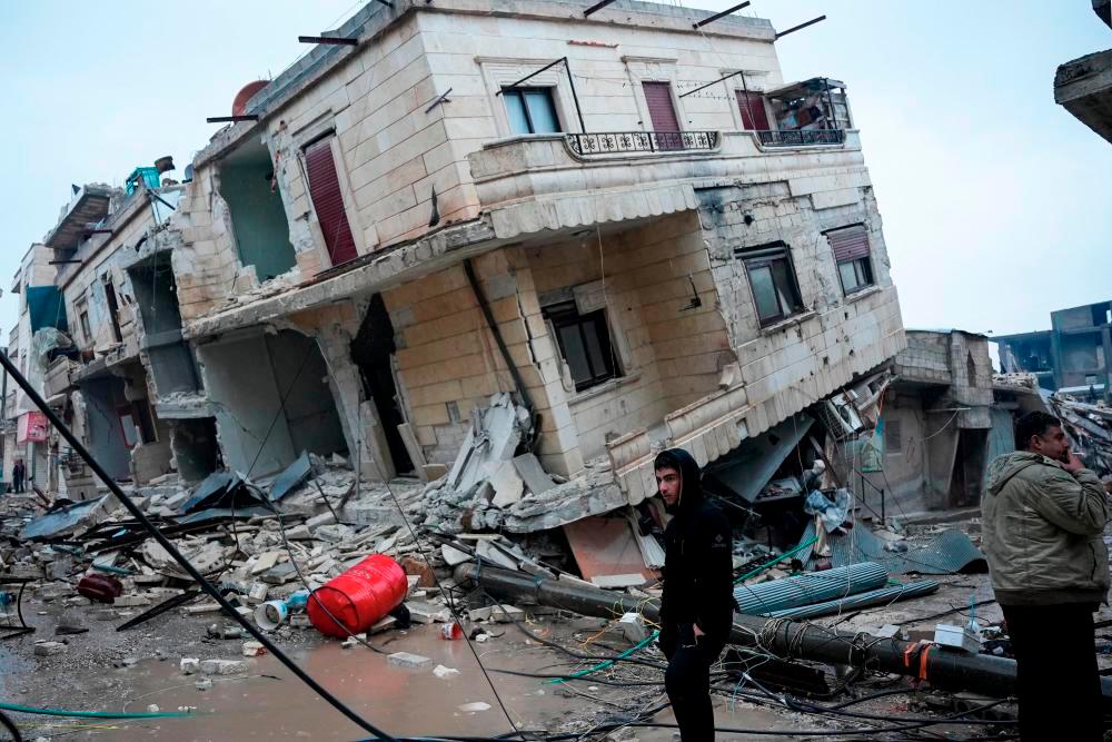 Penduduk berdiri di hadapan bangunan runtuh berikutan gempa bumi di bandar Jandaris, di kawasan luar bandar Afrin di barat laut Syria di bahagian wilayah Aleppo yang dikuasai pemberontak, pada 6 Februari 2023. fotoAFP