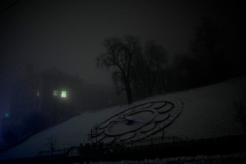 This photograph taken on November 24, 2022, shows the Flower Clock covered in snow and light coming from a window on a foggy night in Kyiv, amid the Russian invasion of Ukraine. AFPPIX