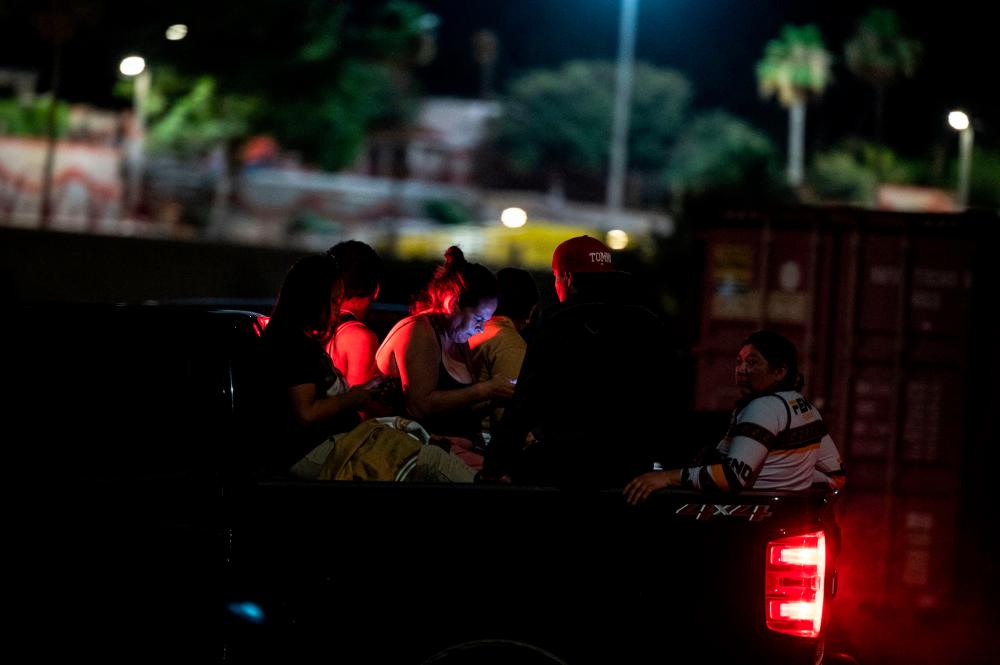 Migrants are transferred on the back of a pick-up truck by the US Border Patrol as they are apprehended by US Border Patrol and National Guard troops in Eagle Pass, Texas, on June 30, 2022. AFPPIX