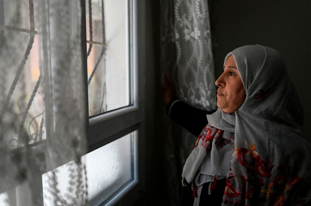 Samira , 43 year-old, who came from Damascus, looks out from a window of her flat in Sanliurfa on May 17, 2022. AFPPIX