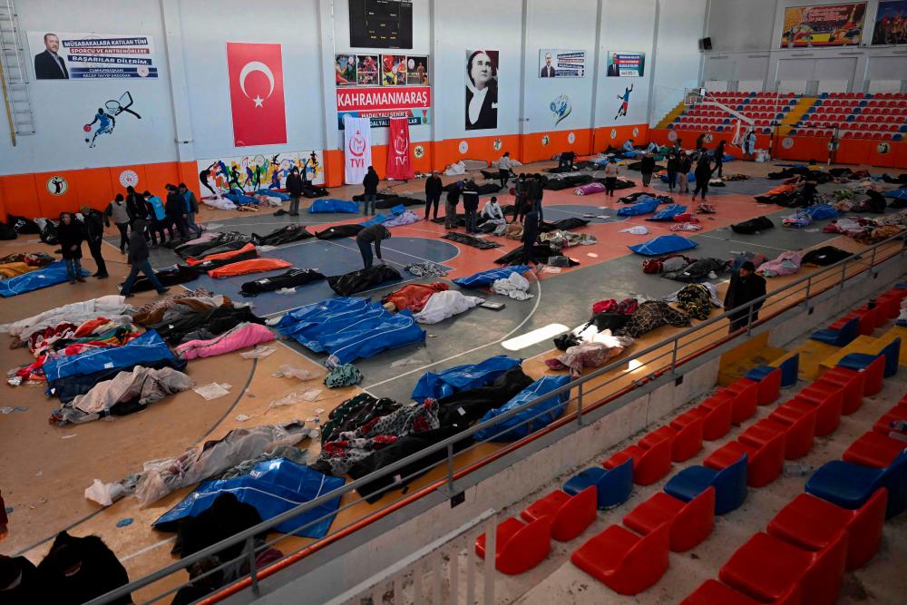 People walk past the bodies of victims stored at the city’s sports hall, two days after a strong earthquake struck the region, in the southeastern Turkish city of Kahramanmaras on February 8, 2023. AFPPIX