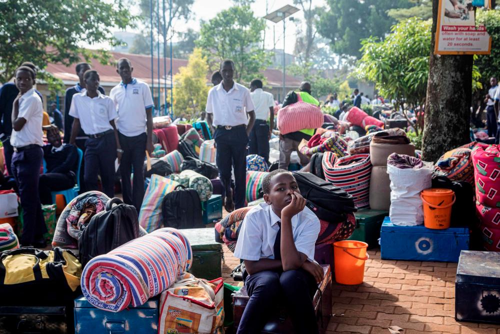 Students wait for their parents with their belongings to leave after a directive of the Health Ministry to close all schools two weeks earlier to curb the spread of Ebola at Naalya Senior Secondary boarding school in Kampala on November 25, 2022. AFPPIX