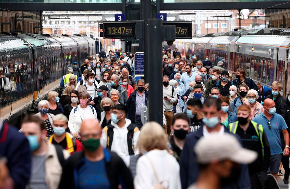 People wearing protective face masks walk along a platform at King’s Cross Station, amid the coronavirus disease (Covi-19) outbreak in London, Britain. -REUTERSPix