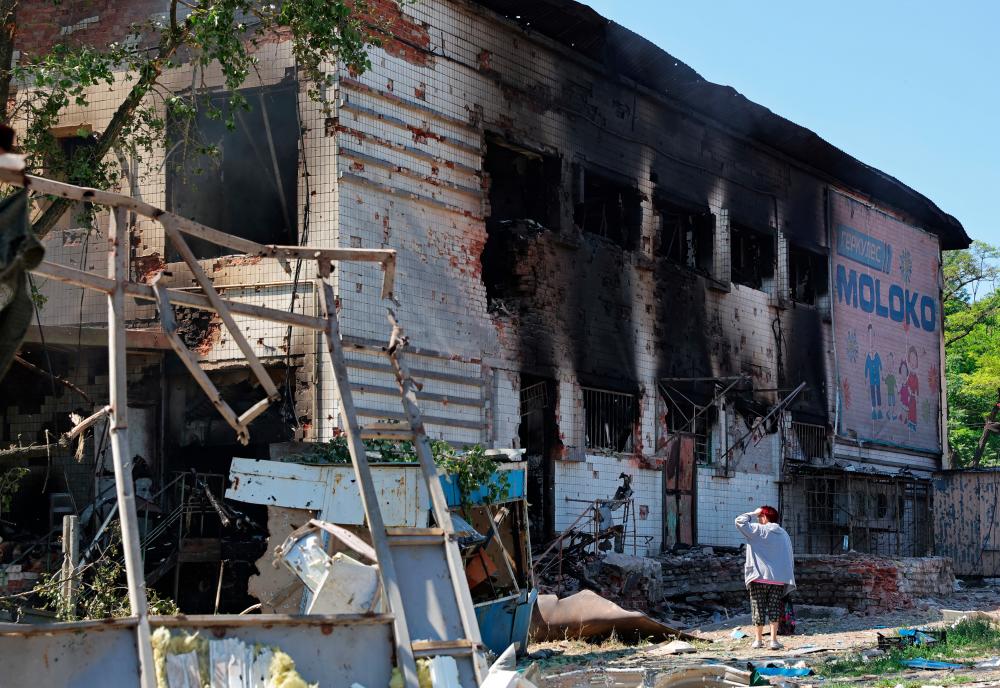 A woman stands next to a building damaged by shelling at a local market in the course of Ukraine-Russia conflict in Donetsk, Ukraine June 19, 2022. REUTERSpix