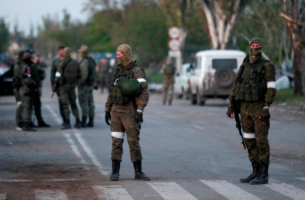 Service members of pro-Russian troops stand guard on a road before the expected evacuation of wounded Ukrainian soldiers from the besieged Azovstal steel mill in the course of Ukraine-Russia conflict in Mariupol, Ukraine May 16, 2022. REUTERSpix