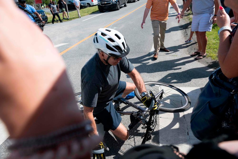 US President Joe Biden falls off his bicycle as he approaches well-wishers following a bike ride at Gordon’s Pond State Park in Rehoboth Beach, Delaware, on June 18, 2022. AFPPIX