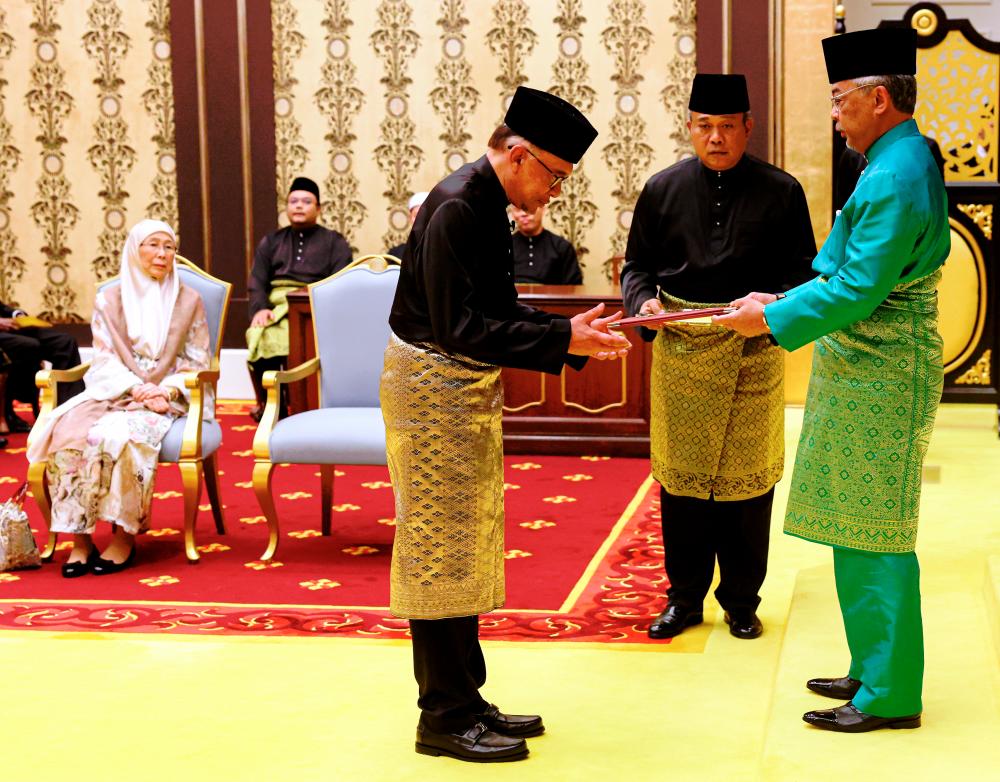 Al-Sultan Abdullah Ri'ayatuddin Al-Mustafa Billah Shah presenting Anwar with the letter of appointment as Malaysia’s 10th prime minister at a ceremony in Istana Negara yesterday. – BERNAMAPIC
